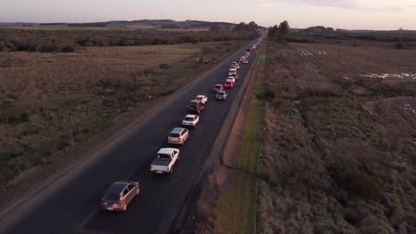 Drone-flight-over-a-traffic-jam-on-a-rural-route-at-sunset-in-Uruguay,-South-America
