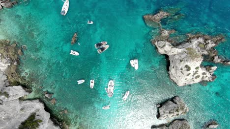 Drone-captures-a-high-altitude-shot-of-the-crystal-blue-sea-off-the-Italian-island-of-Tremiti,-where-several-boats-are-sailing