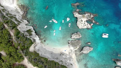 Obere-Luftaufnahme-Des-Strandes-Der-Insel-Tremiti-Mit-Mehreren-Booten,-Die-Im-Kristallblauen-Meer-Segeln