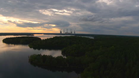 FPV-Flight-over-Lake-and-Forest-with-Power-Plant-in-Distance-during-Golden-Hour