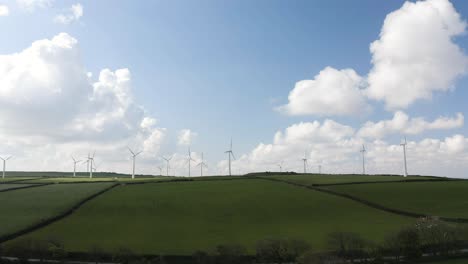 Wind-Farm-In-A-Rural-Landscape-With-Blue-Cloudy-Sky---drone-shot