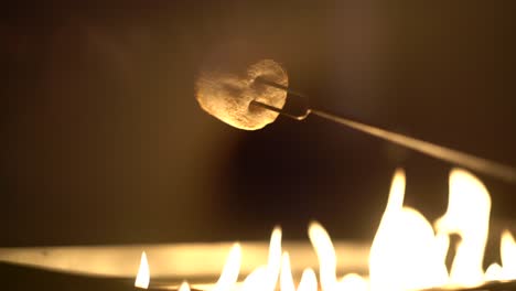 Detail-shot-from-behind-of-tasty-white-marshmallow-roasting-over-gas-fire-pit