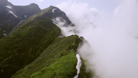 Cinematic-aerial-shot-over-top-hill-peaks-in-the-fog,-untouched-nature-of-mountains