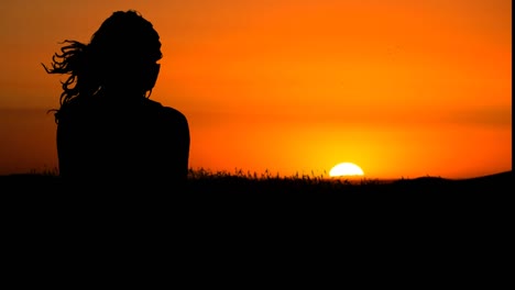 Silhouette-of-woman-looking-at-the-sunset,-mind-wind-blows-on-her-hair