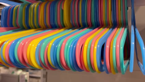 Blue,-yellow,-orange,-pink,-and-green-hangers-of-different-colors-are-suspended-from-the-white-pipe