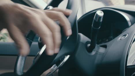 Detail-of-a-hand-on-the-steering-wheel-of-a-jaguar,-the-steering-wheel-turns-in-slow-motion-as-the-driver-is-turning
