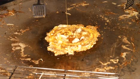 Chef-Prepara-Tortilla-De-Ostras-Tailandesa-Vertiendo-Huevo-Líquido,-Comida-Callejera-En-Tailandia,-Video-En-Cámara-Lenta