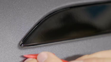 Car-Wrapping-Folie-Mit-Kunststoffwerkzeug-In-Karosserieausschnitt-Schieben,-Nahaufnahme