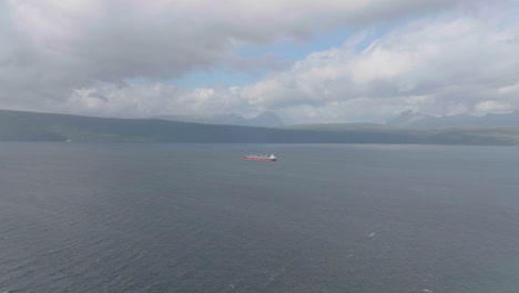 Distant-cargo-ship-anchored-in-Narvik-fjord-of-Northern-Norway,-aerial
