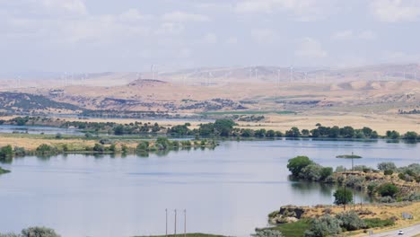 A-wide-shot-of-the-Snake-River-in-Idaho-with-wind-turbines-turning-in-the-distance-on-a-very-hot-summer-day