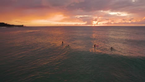 Surfers-waiting-for-ocean-waves-at-sunset,-Oahu,-Hawaii