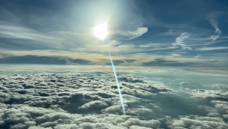 Schöne-Flugszene-Beim-Fliegen-Auf-Reiseflughöhe-über-Wolkenschichten-Und-Mit-Einem-Sonnenstrahl,-Der-Sich-Im-Cockpitfenster-Spiegelt