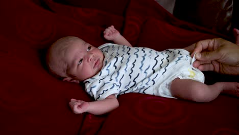 Ruhiges-Entzückendes-Neugeborenes-Baby,-Das-Schaut,-Während-Mutter-Knopf-Auf-Bodysuit-Schließt