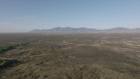 Wide-aerial-footage-flying-across-the-Arizona-desert-in-the-morning-sun-showing-a-winding-road-and-mountains-in-the-background