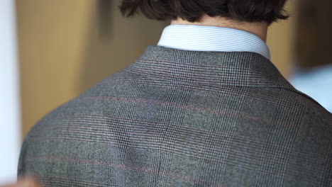 Showing-hem-of-tweed-suit-jacket-collar-on-boutique-customer,-close-up