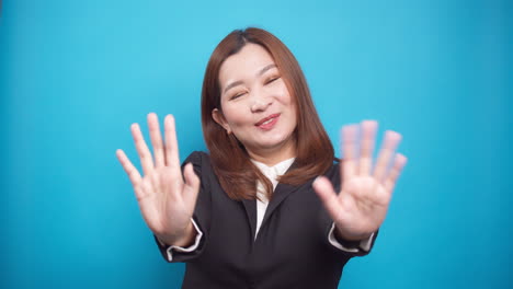 Zeitlupenporträt-Einer-Asiatischen-Glücklichen-Geschäftsfrau-Winkt-Mit-Der-Hand-Für-Werbung,-Die-Auf-Blauem-Hintergrund-Isoliert-Ist