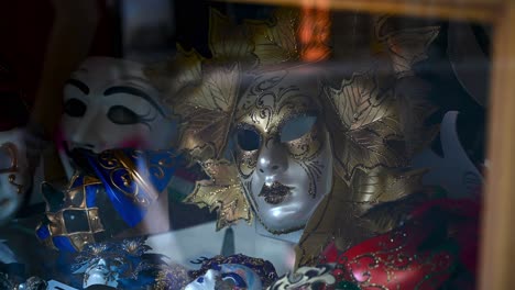 Beautiful-Venetian-Carnival-Masks-displayed-in-a-shop-in-Venice-with-reflection-of-people-passing-by-on-the-streets