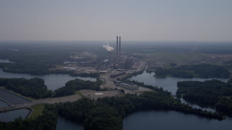 Wide-aerial-hyperlapse-timelapse-of-a-power-plant-on-the-shores-of-a-lake-on-a-hazy-afternoon