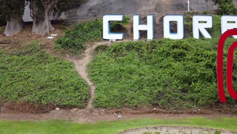 Drone-video-of-a-red-sign-reading-"Peru"-and-behind-it-on-a-green-hill-another-sign-reading-"Chorrillos"-the-name-of-the-district-in-which-this-was-recorded