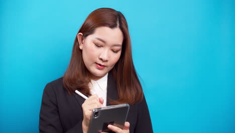 Schöne-Asiatische-Geschäftsfrau-In-Einem-Schwarzen-Anzug,-Der-Ein-Digitales-Tablet-Für-Die-Planung-Von-Online-arbeiten-Mit-Drahtloser-Technologie-Auf-Blauem-Hintergrund-Verwendet-2