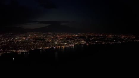 Night-view-of-Catania-city,-in-Sicilia-taken-at-1000m-high-from-a-plane-cockpit,-with-the-shape-of-the-Etna-volcano-at-the-back