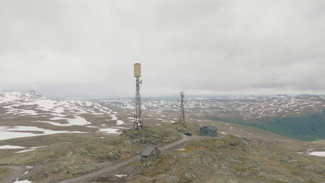 Cell-tower-on-Storhovd-mountain-surrounded-by-patchy-snow,-Norway