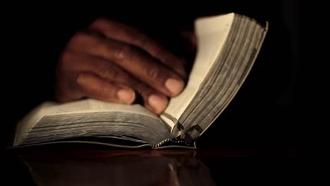 Praying-to-God-with-hand-on-bible-black-background-with-people-stock-footage-1