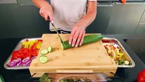 Eye-perspective-on-a-cutting-board-with-knife-and-sliced-cucumber-with-other-vegetables-and-tablet-with-recipe