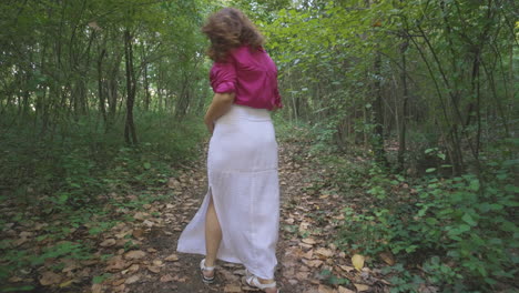 Pregnant-Woman-Expectant-Mother-Walking-Alone-in-Forest-Path-Surrounded-by-Vegetation-Trees,-Pretty-Casual-Dressed-Mom-Turning-Around-Stroking-Touching-Her-Belly-Smiling,-Childbearing-and-Tenderness