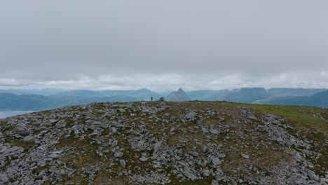Excursionista-De-Pie-En-La-Cima-De-La-Montaña-Rocosa-En-Luroy,-Condado-De-Nordland,-Noruega