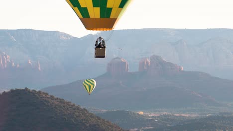Hot-air-balloon-descends-with-Cathedral-Rock-in-background,-Sedona,-Arizona