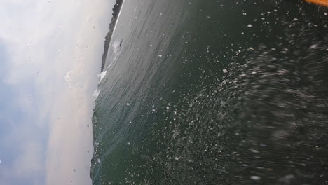 Vertical-POV,-person-surfing-on-ocean-on-a-longboard,-gloomy-day