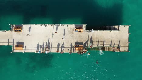 Still-drone-shot-of-a-pier-with-people-in-Porto-Santo,-Madeira