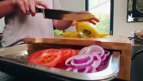 Peppers-are-cut-on-a-cutting-board-with-other-vegetables-like-tomato-or-onion-with-a-tablet-on-it