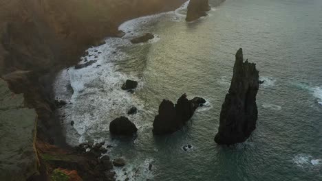 Revealinjg-drone-shot-of-the-small-black-beach-next-to-the-cliffs-on-the-coast-of-Madeira