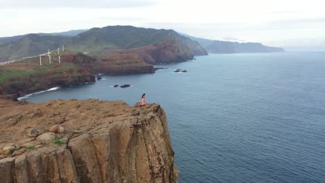 Drone-shot-of-a-woman-walking-on-the-edge-of-a-cliff-in-a-dress-in-the-wind-in-Madeira