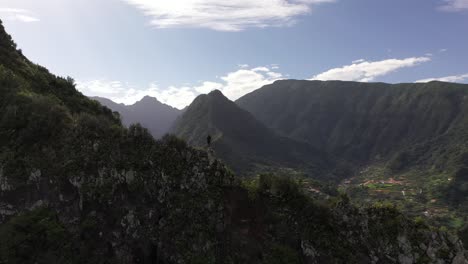 Circling-drone-clip-of-a-man-standing-on-the-edge,-surrounded-by-beautiful-nature-in-Madeira