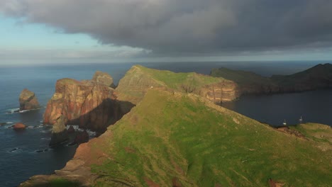 Drohne-Schoss-über-Die-Grünen-Klippen-Von-Madeira-Mit-Einer-Sturmwolke-Und-Zwei-Kleinen-Weißen-Booten-In-Der-Ferne
