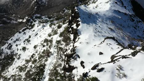 Ein-Fußweg-Mit-Spuren-Im-Schnee,-Der-Den-Berg-Pico-Ruivo-In-Madeira-Mit-Seiner-Nebligen-Und-Wolkigen-Landschaft-Hinuntergeht