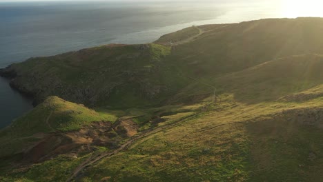 Drone-shot-of-Green-fields-and-small-trails-on-the-cliff-of-Madeira-during-sunset