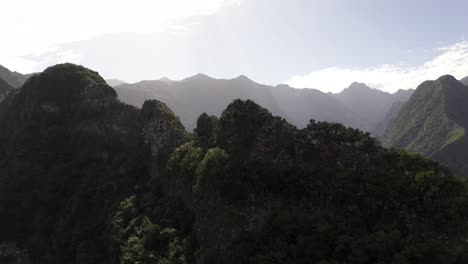 Cinematic-drone-shot-going-over-a-mountain-ridge-to-reveal-the-beautiful-valley-below-with-a-small-village-in-madeira