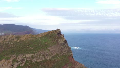 Drone-shot-over-the-cliff-of-a-peninsula-in-Madeira-with-a-small-watch-tower-or-lighthouse-on-the-top