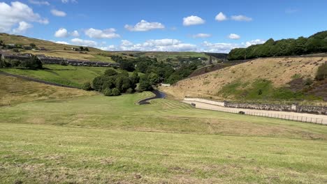 Rural-country-houses-cottages-on-a-hillside-in-Marsden-West-Yorkshire-United-Kingdom,-surrounded-by-hills-and-fields-at-the-foot-of-a-dam