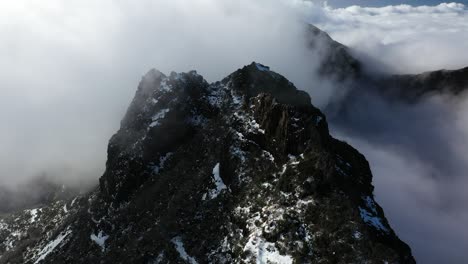 Drohnenaufnahme-Des-Dunklen-Und-Schwarzen-Gipfels-Des-Berges-Pico-Ruivo-In-Madeira-Mit-Dünnen-Wolken,-Die-Herumfliegen