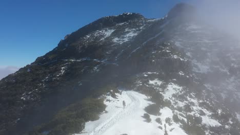 Eine-Frau-Geht-In-Einer-Roten-Jacke-Auf-Dem-Schneebedeckten-Pfad-Auf-Dem-Berg-Pico-Ruivo-In-Madeira