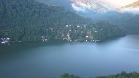 Homes-of-small-village-on-shore-of-Lake-Tarnita,-Romania-seen-from-drone