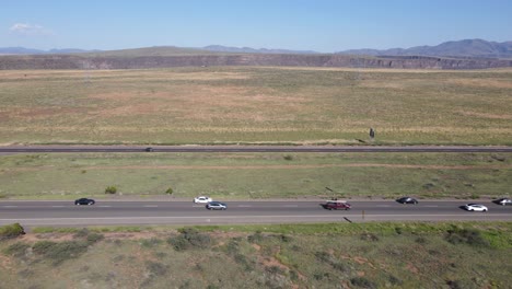 Drone-flying-along-the-side-of-the-highway-showing-busy-traffic-and-a-blue-sky-and-prairie-in-the-background