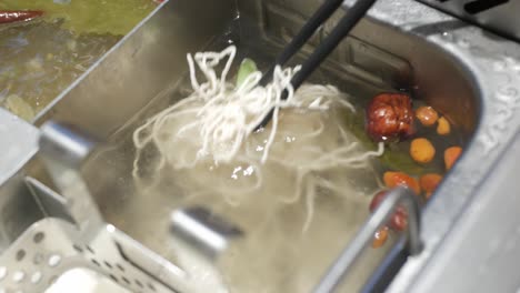 Putting-fresh-handmade-egg-noodle-intoboiled-szechwan-hotpot-chinese-style-cuisine-asian-soup