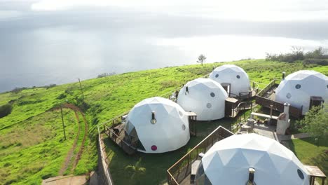 Drone-shot-over-igloo-glamping-tents-in-Madeira-and-then-tilting-down-over-the-cliff-edge-to-the-Atlantic-ocean