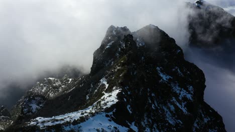 Aerial-shot-of-the-black-peak-of-the-mountain-Pico-Ruivo-in-Madeira-with-snow-and-thin-clouds
